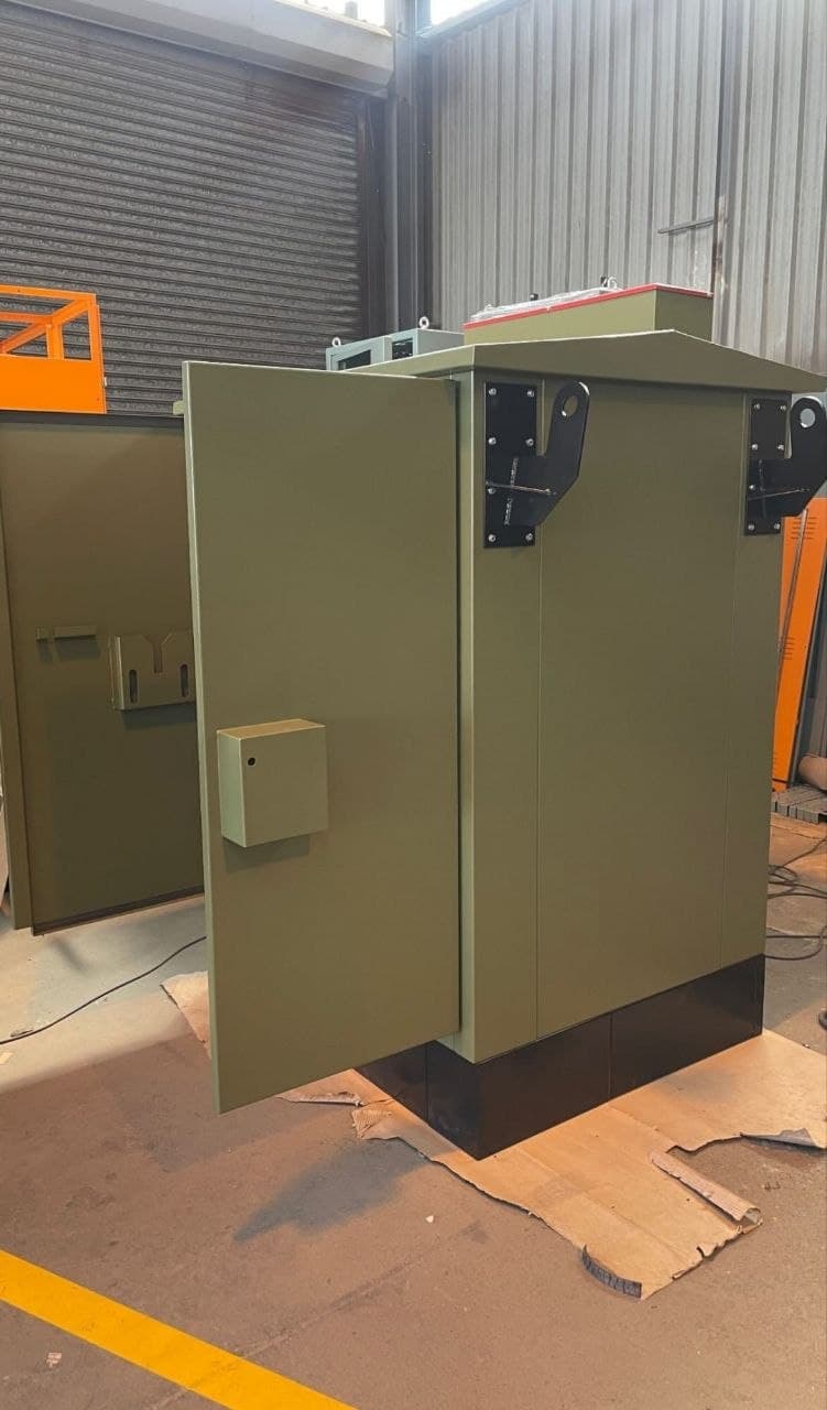 Heavy-duty green steel equipment enclosure in a workshop